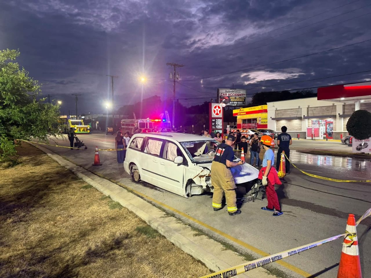 Firefighters with a wrecked white minivan at National Night Out, with emergency vehicles and caution tape nearby